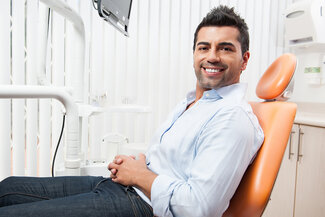 man sitting in dental chair, restorative dentistry Hartsdale, NY